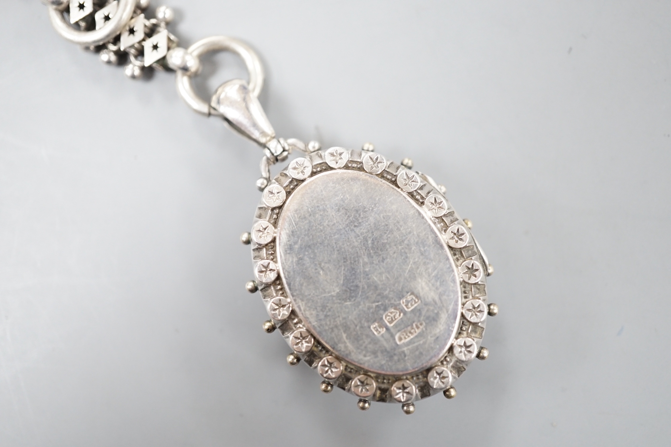 A late Victorian silver oval locket, on a white metal albertina, 49cm.